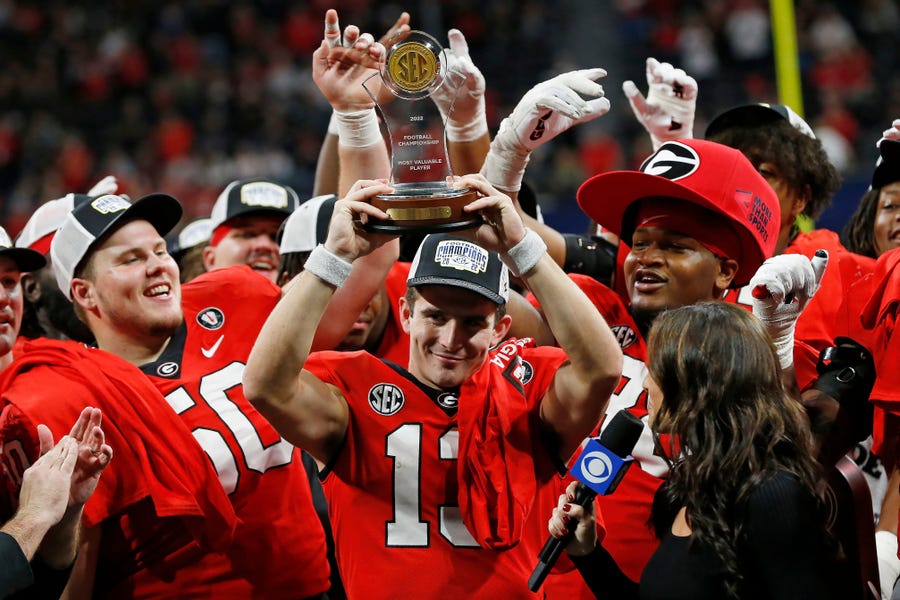 Georgia quarterback Stetson Bennett  raises the SEC Championship MVP trophy after a victory against LSU.