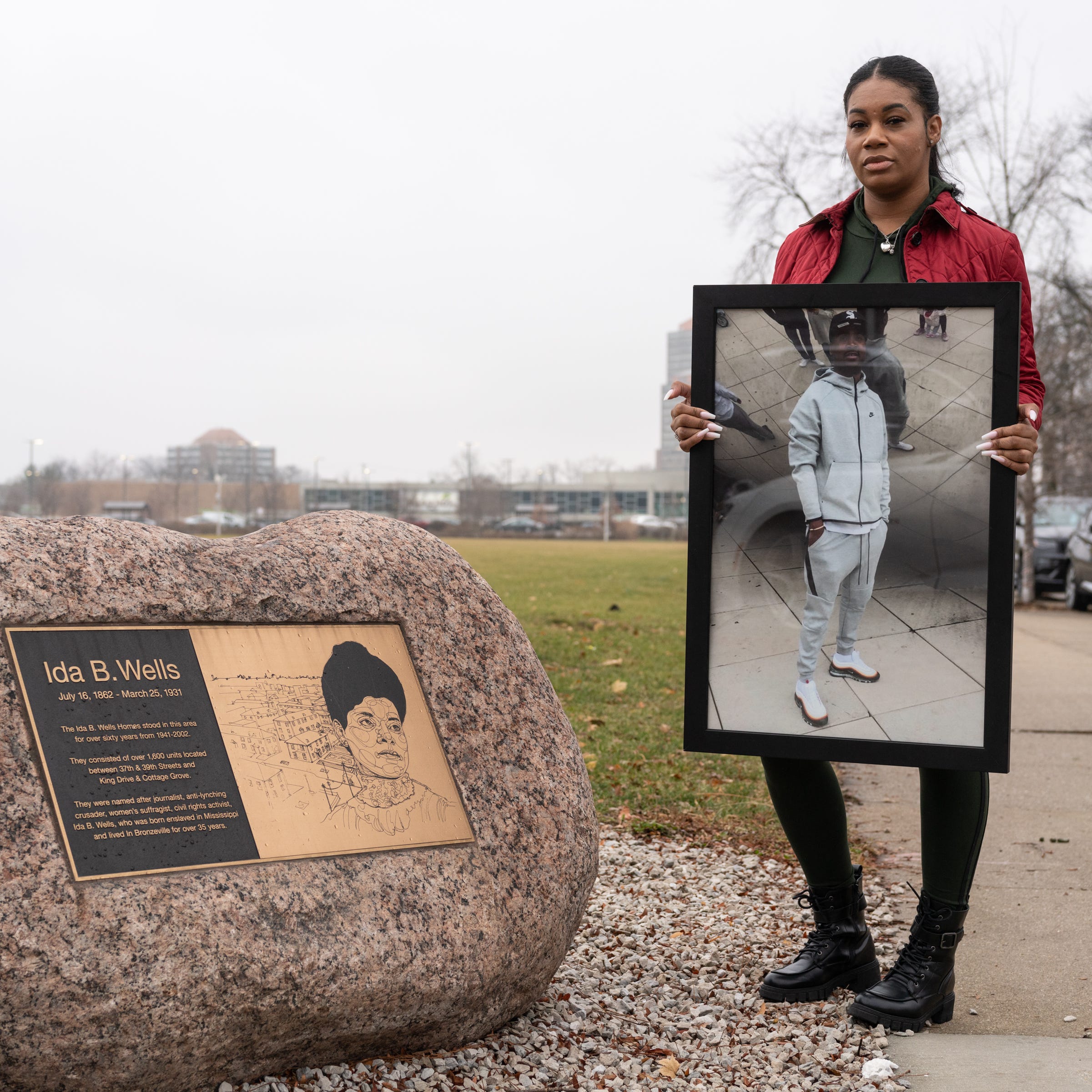 Shawntell Nile, 33, poses with a photo of her late bother, JaJuan, at the former Ida B. Wells Homes site in Chicago where he lived, on Dec. 10, 2022.