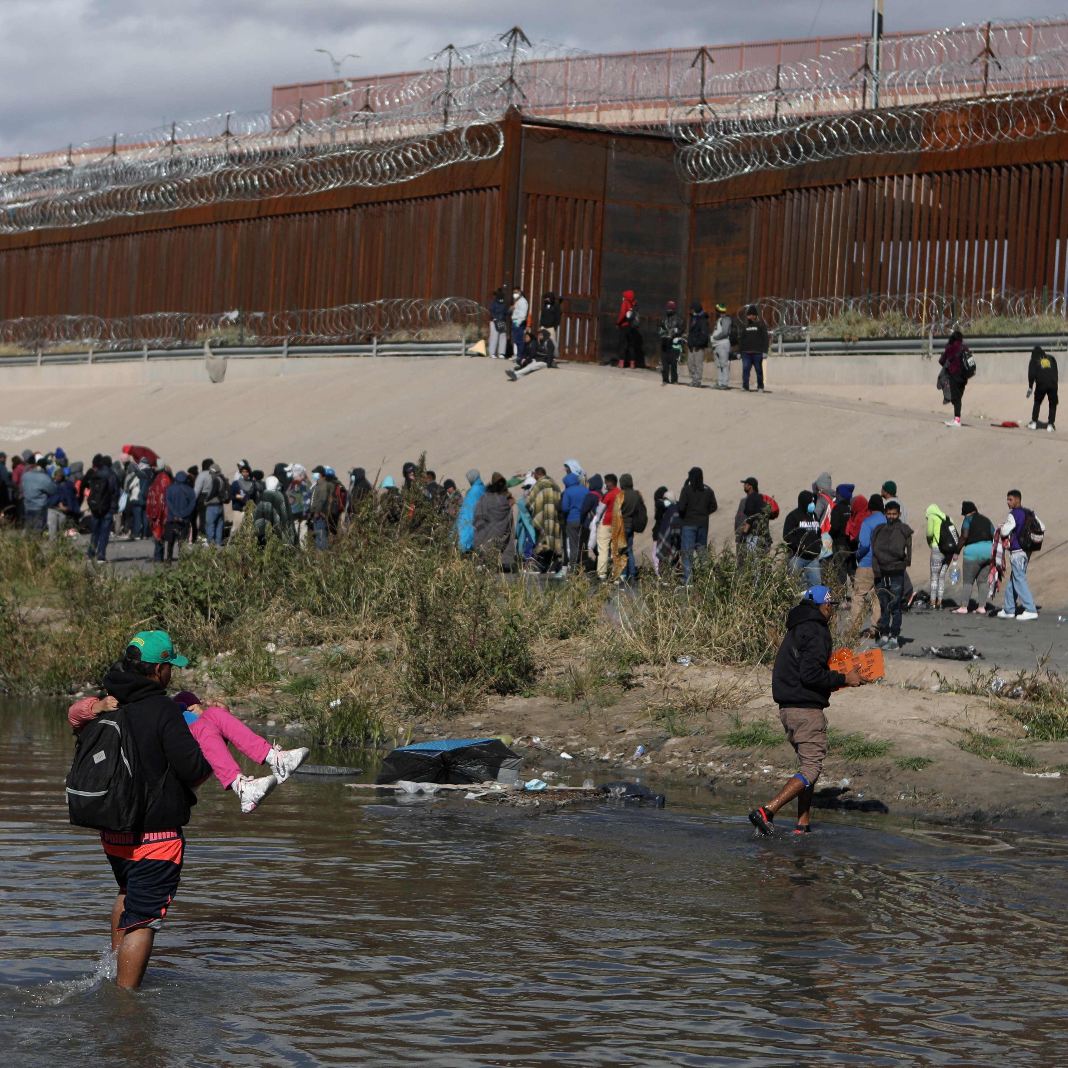 December 13, 2022: Migrants walk across the Rio Grande to surrender to US Border Patrol agents in El Paso, Texas, as seen from Ciudad Juarez, Chihuahua state, Mexico.