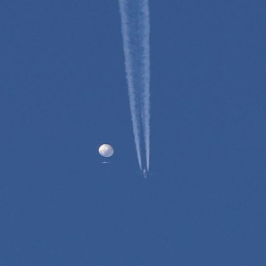 In this photo provided by Brian Branch, a suspected Chinese spy balloon drifts above the Kingstown, N.C. area, with an airplane and its contrail seen below it before the U.S. fighter jets shot down the balloon over the Atlantic Ocean on Saturday.