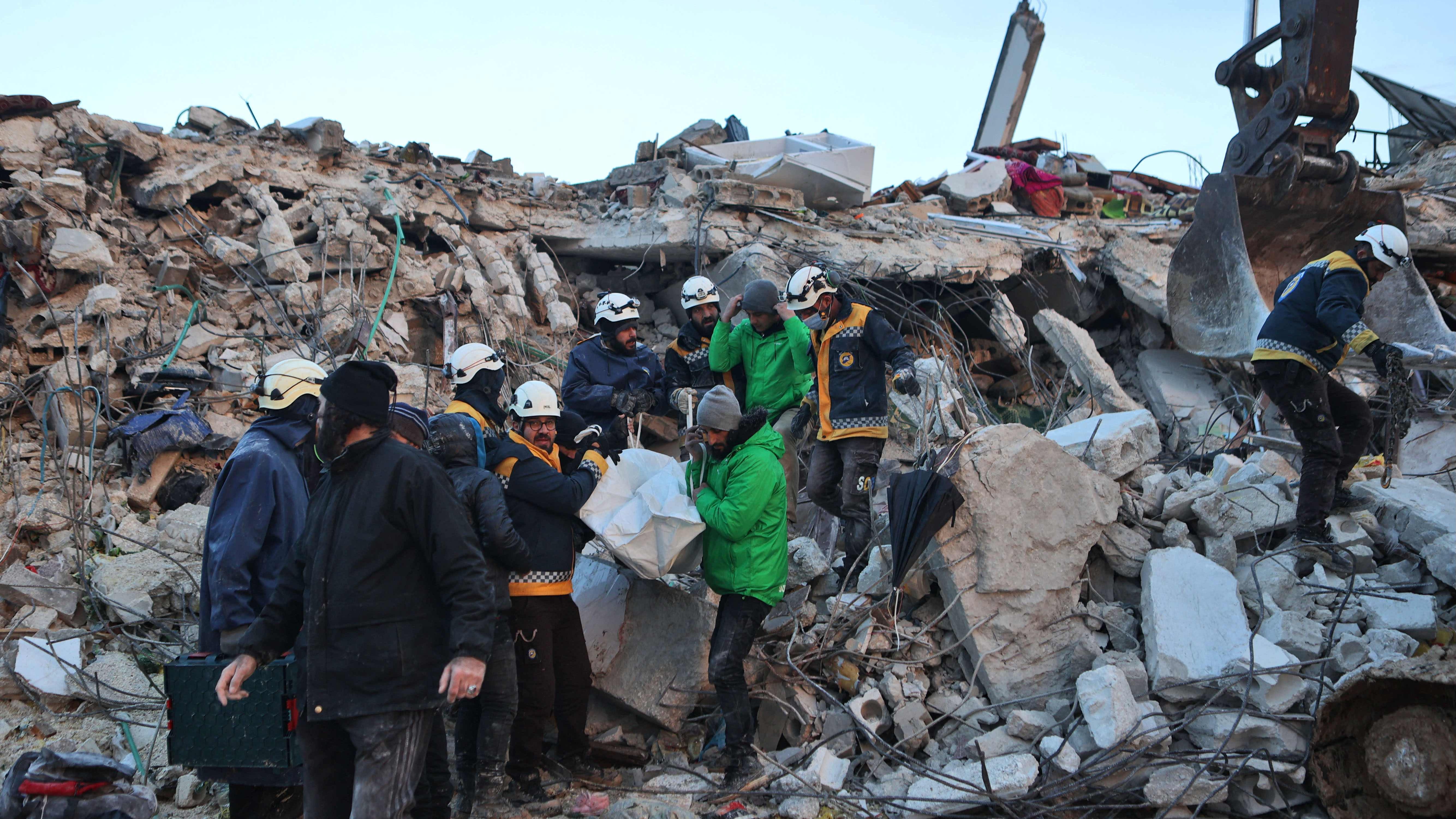 Syrian rescuers remove a body from the rubble of a collapsed building on February 6, 2022 in the town of Sarmada, in Syria's rebel-held northwestern Idlib province, as a search operation continues following a deadly earthquake.