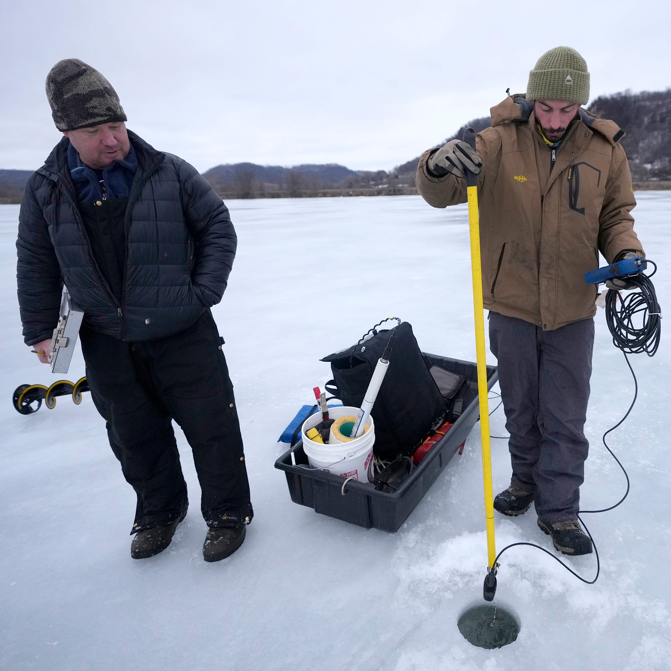 Jeremy King (right), a water quality technician with the Wisconsin Department of Natural Resources, uses a device to measure the turbulence of the water in the backwaters of the Mississippi River near Alma as Shawn Giblin, a DNR Mississippi River water quality specialist, looks on in Alma Feb. 15. High water flowing through the river over the last decade is disturbing winter resting spots for fish like bass and bluegill.