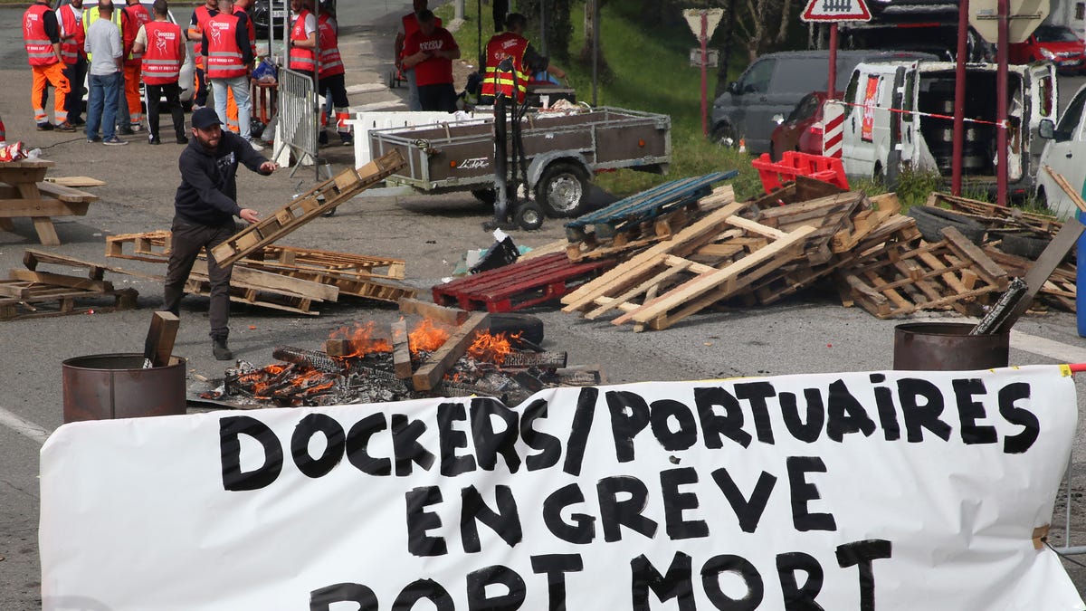 Striking dockers occupy a road leading to the port of Bayonne with a banner reading "Dockers striking, dead port" in Tarnos, southwestern France, Wednesday, March 8, 2023.