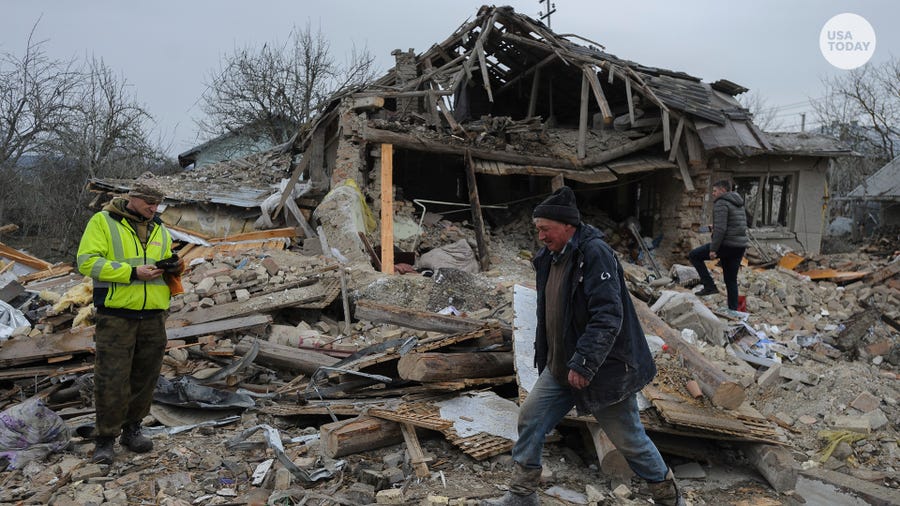 Villagers walk in the debris of private houses ruined in Russia's night rocket attack in a village, in Zolochevsky district in the Lviv region, Ukraine, Thursday, March 9, 2023.