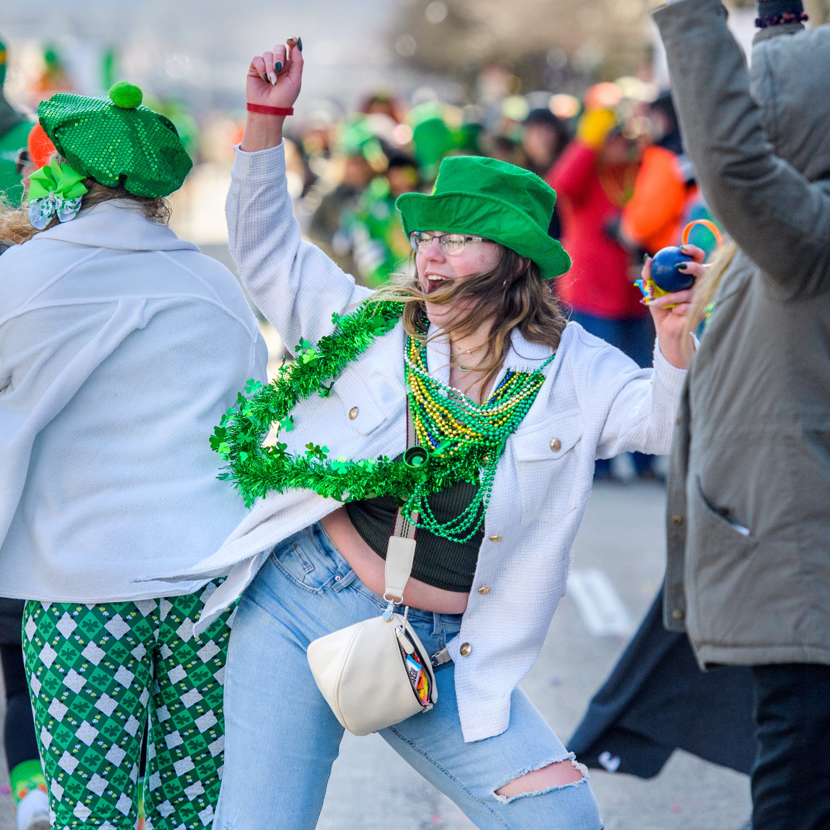 Laden with beads, Mattie Tracy of Peoria bumps hips with a parade volunteer during the St. Patrick's Day Parade on Friday, March 17, 2023 through downtown Peoria. Despite low temperatures and a cold breeze, hundreds turned out for the annual event.