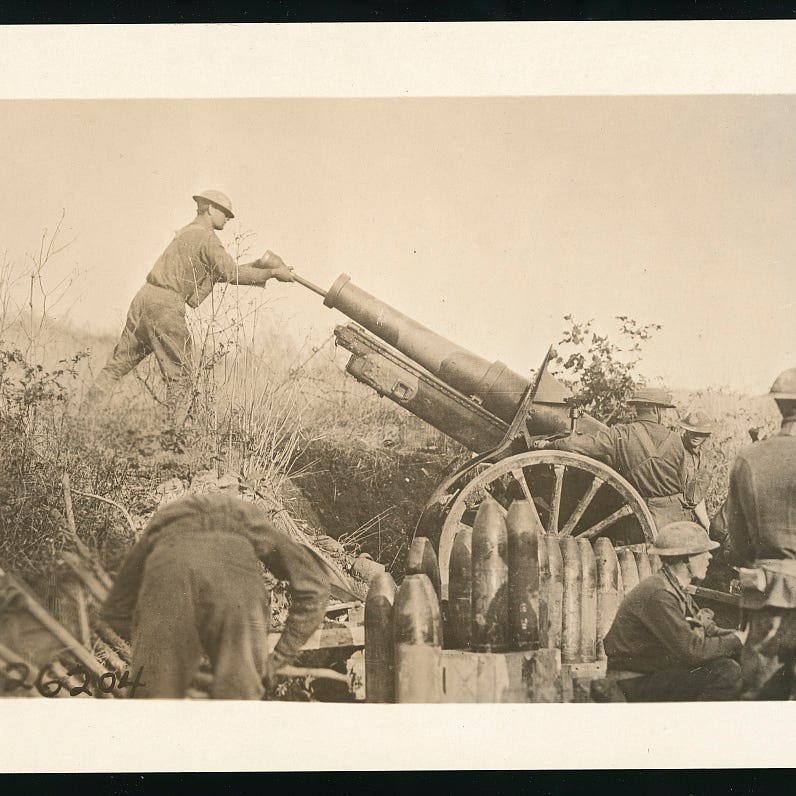 Photograph shows American soldiers from the 324th Field Artillery Regiment or the 158th Field Artillery Brigade around a camouflaged 155 mm howitzer with shells nearby, one soldier stands in front of the cannon holding a tool in the barrel, assisting the 29th Infantry Division, in Cote de Roche, near Samogneux, Meuse, France during World War I.