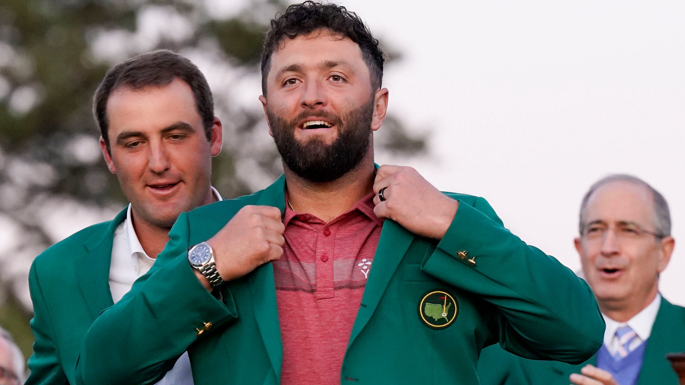 Scottie Scheffler (left) helps Jon Rahm into his green jacket after Rahm's Masters win.