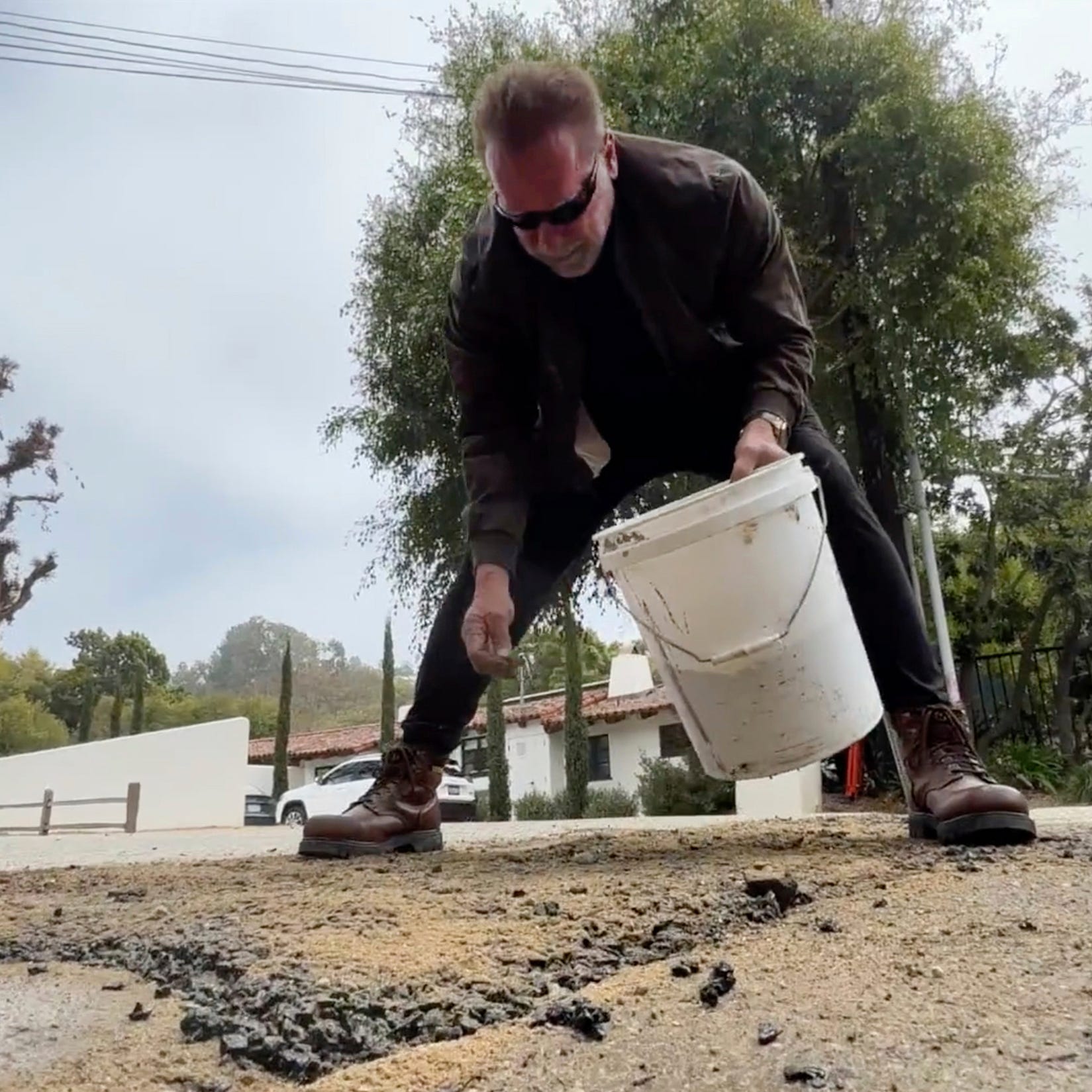 This video still image provided by The Office of Arnold Schwarzenegger, shows former California Governor Arnold Schwarzenegger, repairing a pot hole on a street in his Los Angeles neighborhood on Tuesday, April 11, 2023. Fed up by an enormous pothole in his neighborhood, Schwarzenegger picked up a shovel and filled it himself. (The Office of Arnold Schwarzenegger via AP) ORG XMIT: LA211