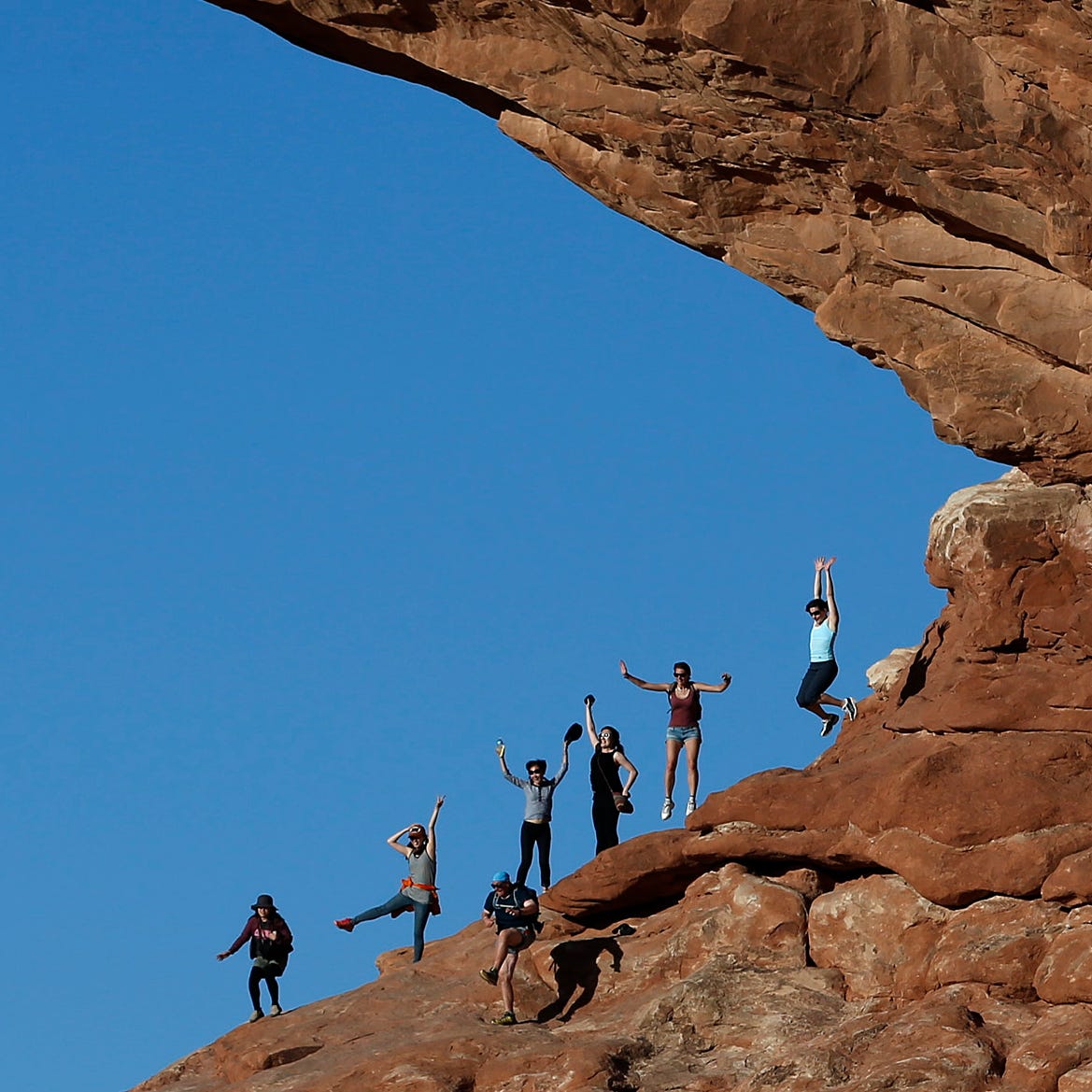 A group of visitors try to jump in unison at North Window in Arches National Park on June 21, 2013.