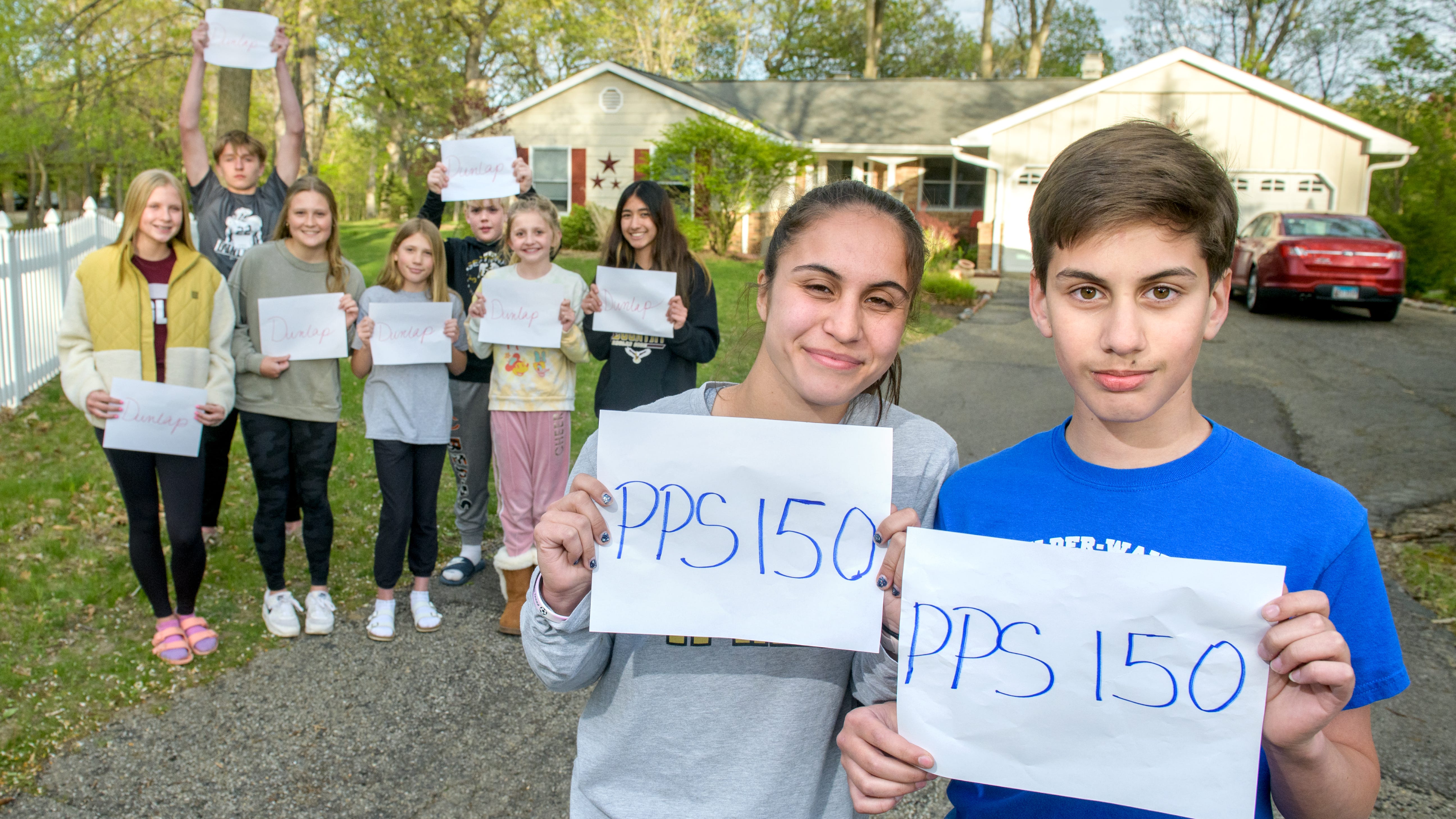 Matthew Seipold, right, 11, and sister Izzy, 17, stand with some of their neighborhood friends and classmates in the driveway of their home of ten years on W. South Forest Trail in the Ravinwoods subdivision. Their parents John Seipold and Zilda Delgado were recently informed that their children, who've always attended Dunlap Schools, will now have to attend Peoria Public Schools because their home actually falls within PPS boundaries. The couple are trying to get the property annexed into the Dunlap district to avoid separating their kids from their friends.