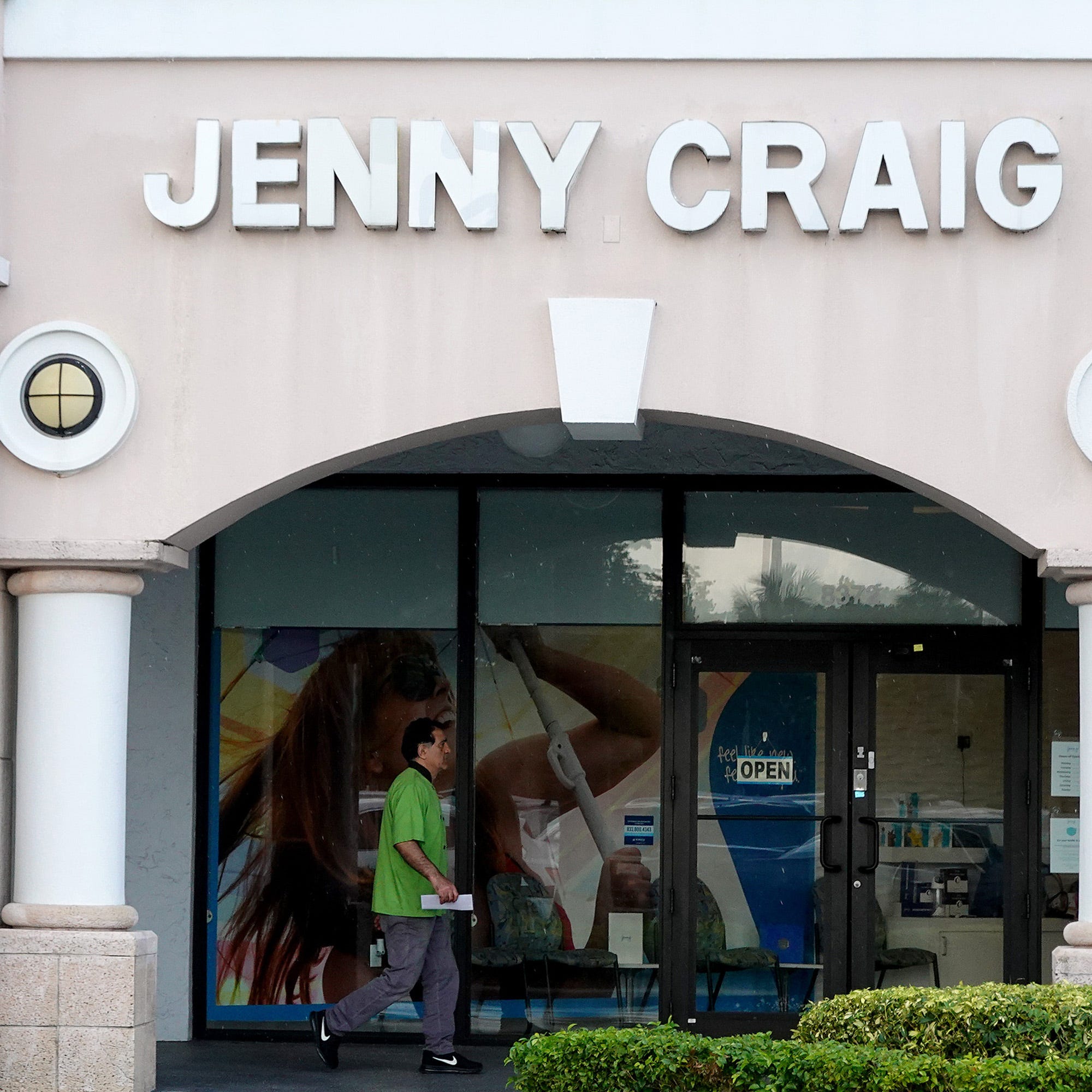 A person walks past a Jenny Craig weight loss store on April 28, 2023 in Miami, Florida. Reports indicate that the Jenny Craig company will undergo potential mass layoffs as it begins a hunt for a buyer.