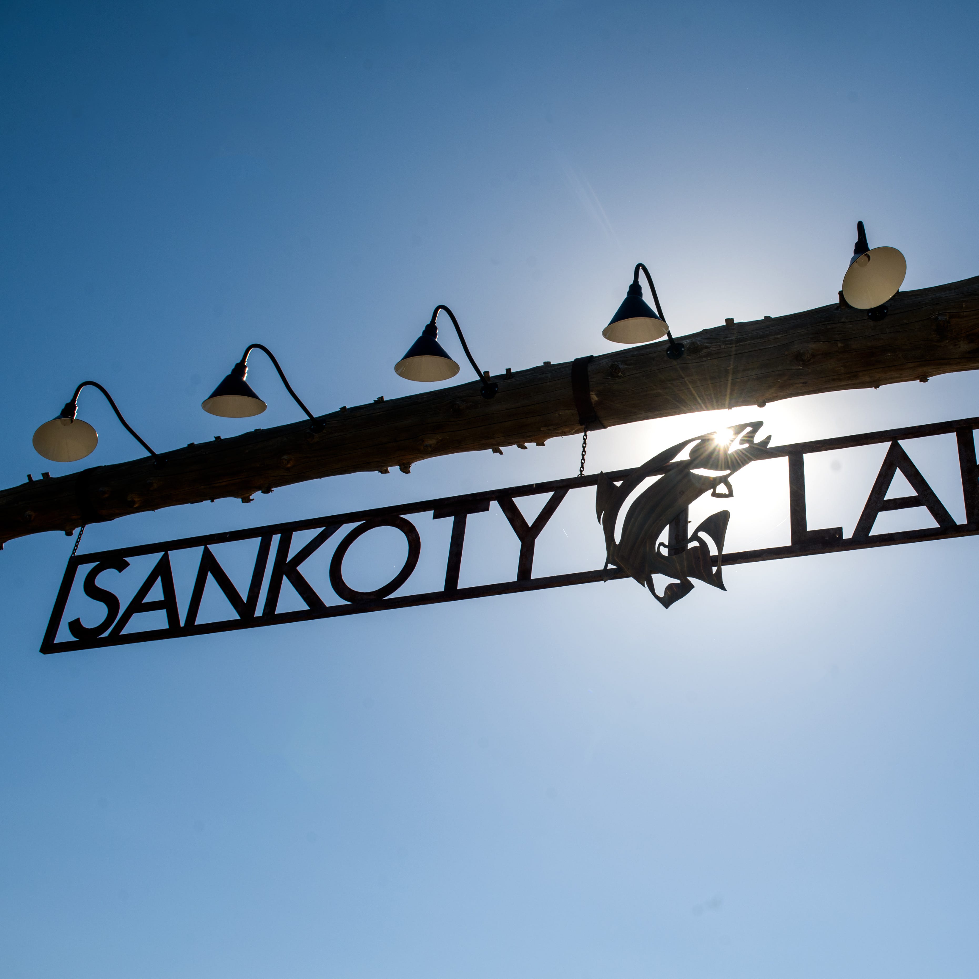 The sun shines through the Sankoty Lakes Resort logo hanging at the entrance to the shuttered property in Spring Bay.