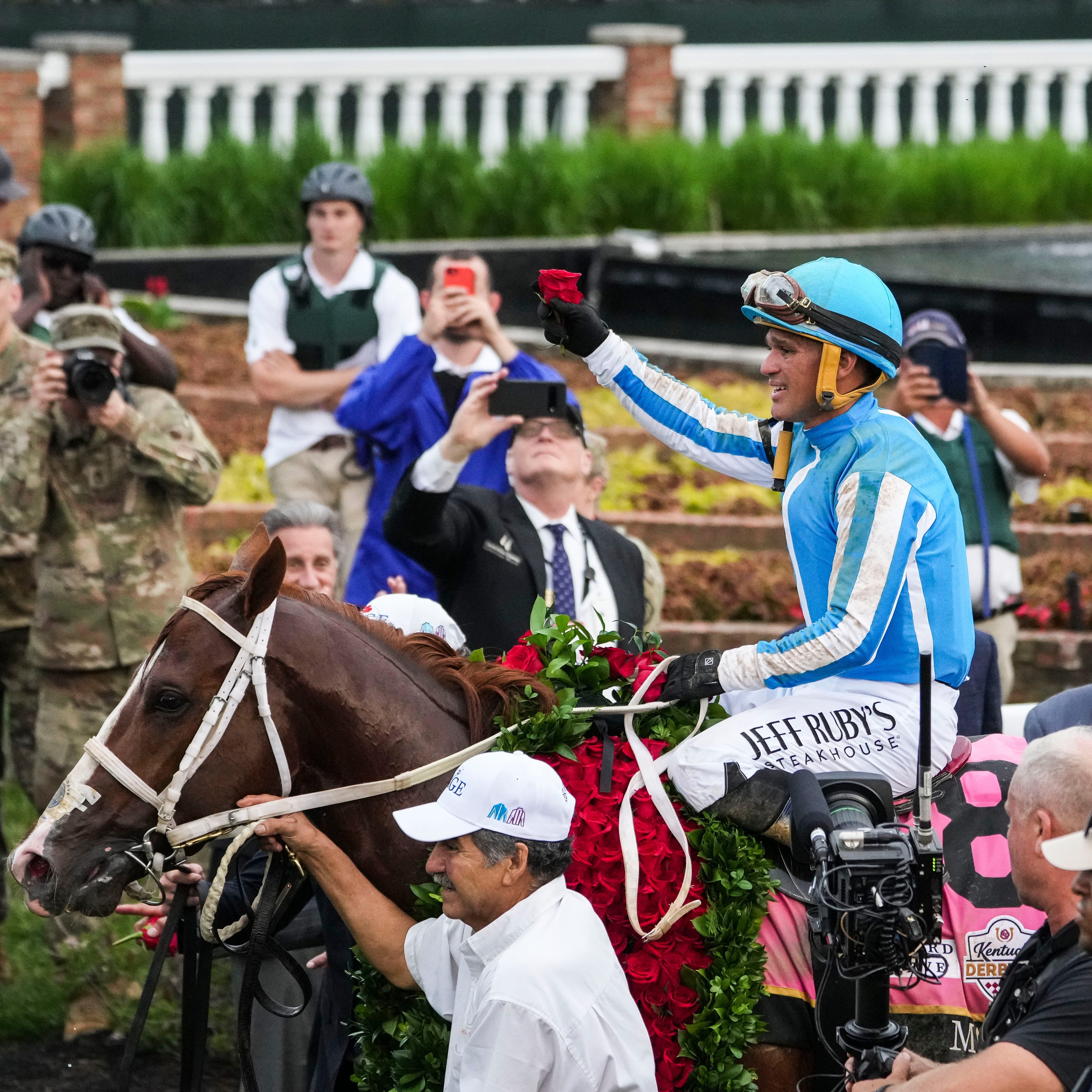 Jockey Javier Castellano holds a rose as he and Mage walk to the Winner's Circle after winning the 149th Kentucky Derby Saturday.