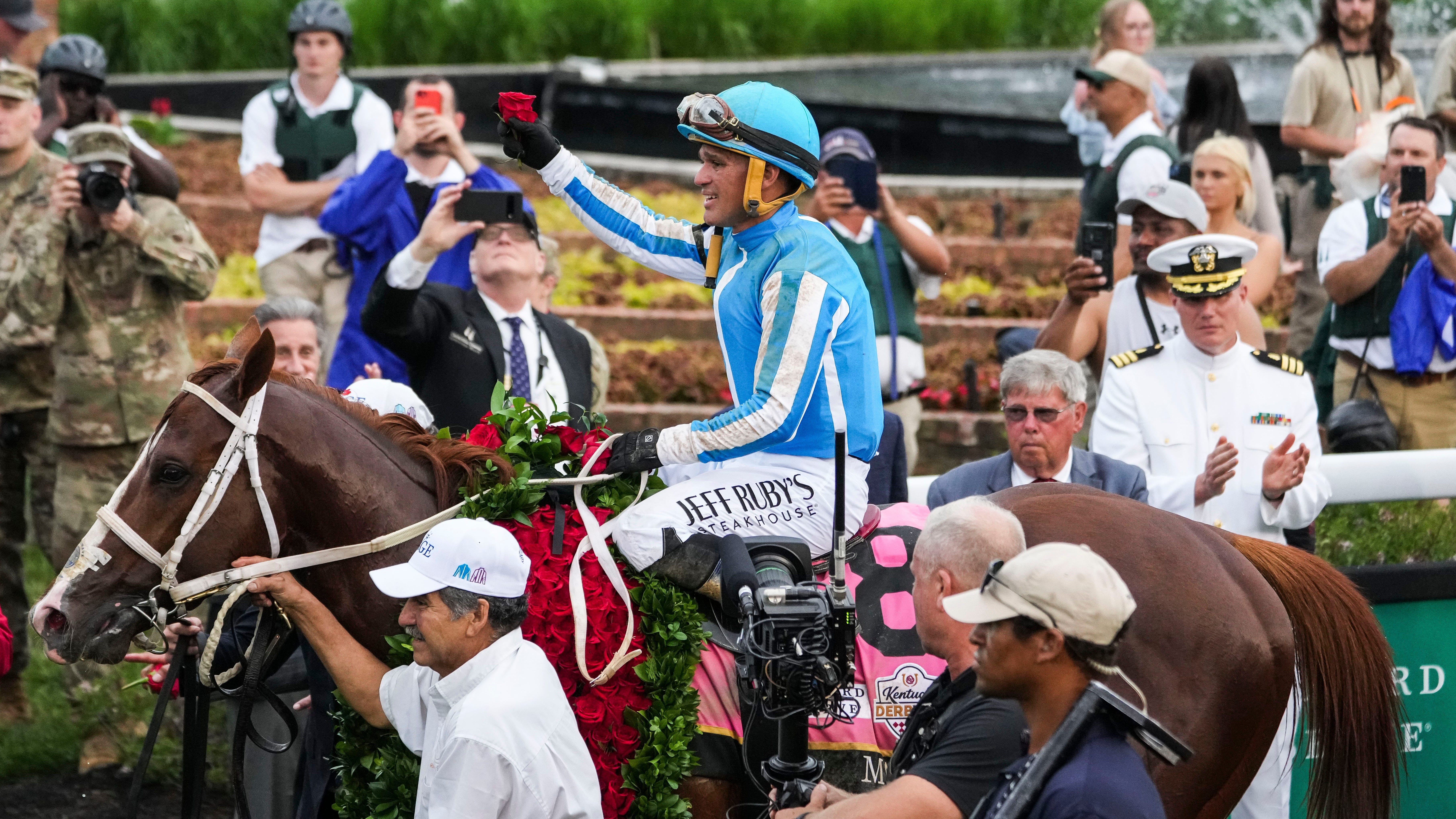 Jockey Javier Castellano holds a rose as he and Mage walk to the Winner's Circle after winning the 149th Kentucky Derby Saturday.