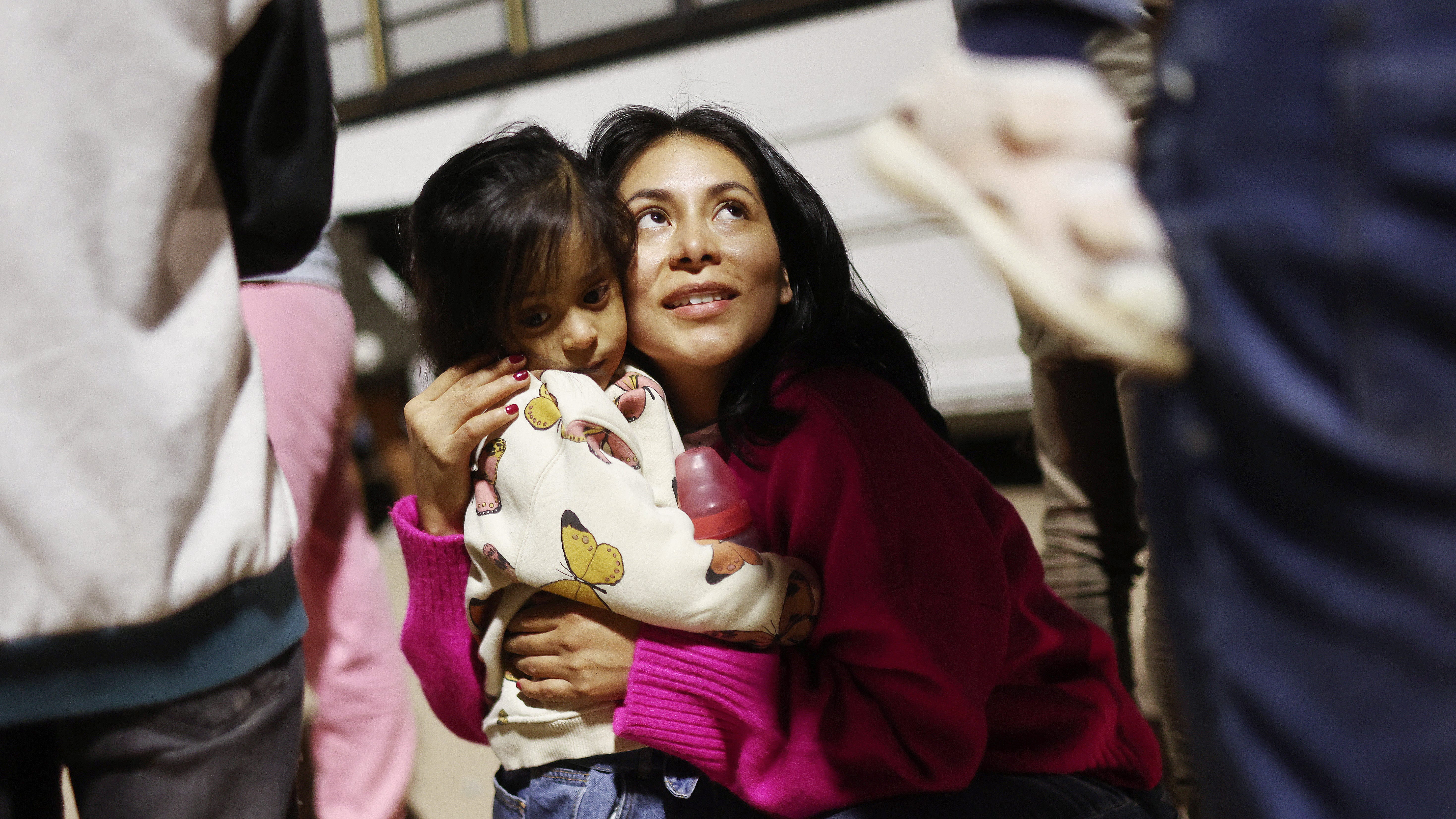 YUMA, ARIZONA - MAY 11: Peruvian immigrant family members, who are seeking asylum in the United States, embrace as they wait to board a bus during processing by U.S. Border Patrol agents in the early morning hours after crossing into Arizona from Mexico on May 11, 2023 in Yuma, Arizona. A surge of immigrants is expected with today's end of the U.S. government's Covid-era Title 42 policy, which for the past three years has allowed for the quick expulsion of irregular migrants entering the country. Over 29,000 immigrants are   currently in the custody of U.S. Customs and Border Protection ahead of the sunset of the policy later today.