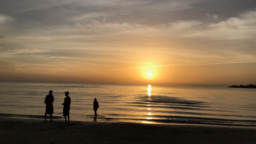 People are silhouetted on a beach at sunset in Negril, Jamaica on May 21, 2017.