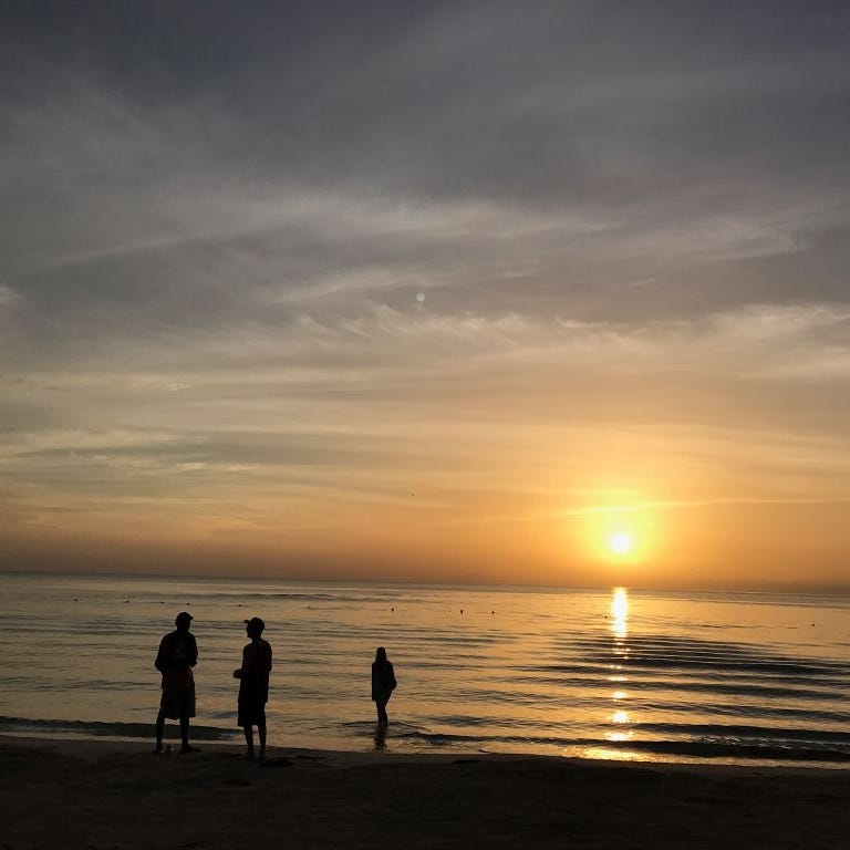 People are silhouetted on a beach at sunset in Negril, Jamaica on May 21, 2017.