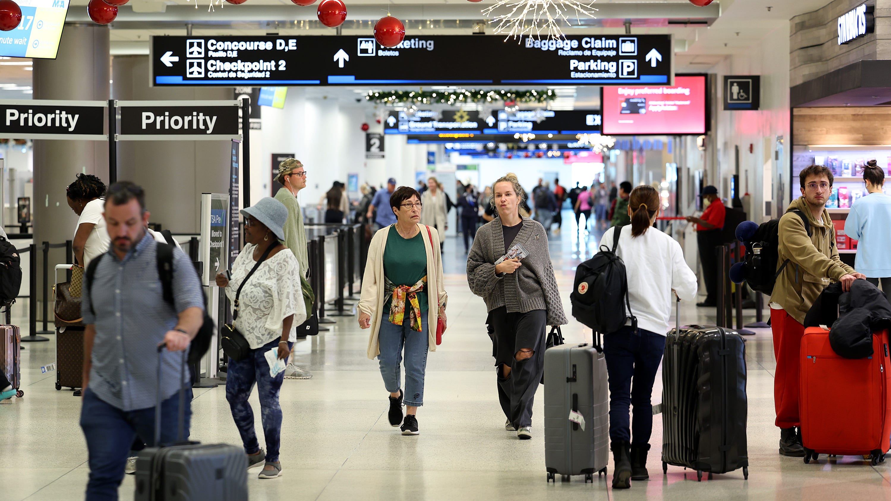 Travelers walk through Miami International Airport on December 19, 2022 in Miami, Florida. (Photo by Joe Raedle/Getty Images)