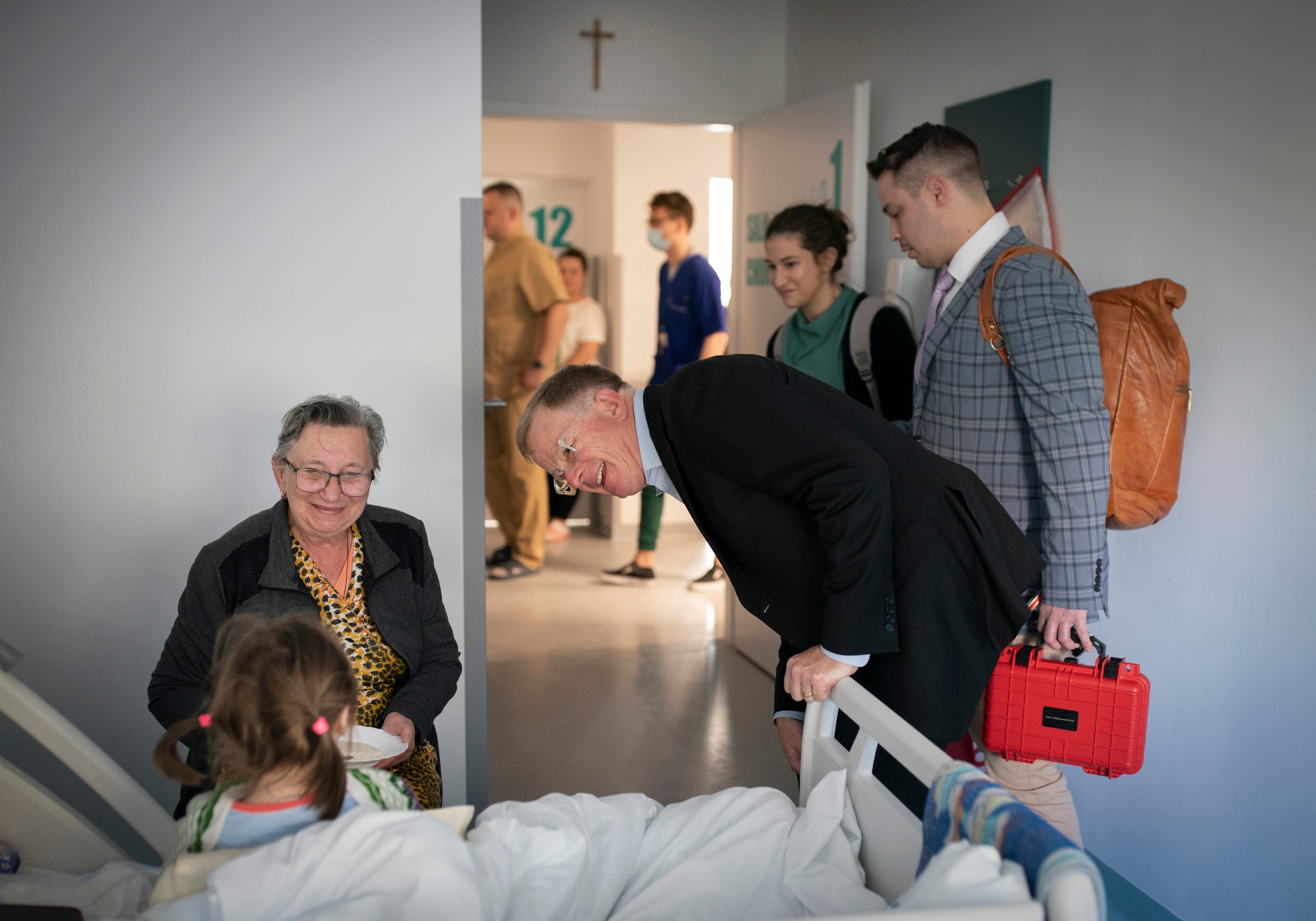 Valentina Ukhvatova, 75, of Dnipro smiles as Dr. David Brown, a plastic surgeon from the University of Michigan makes morning rounds on Tuesday, May 16, 2023 to check on her great granddaughter Evheniia Ukhvatova, 6, while she recovers from surgery she had the day before in Leczna, Poland. Evheniia Ukhvatova had surgery on burn scars that cover the backs of her legs and feet due to the contractures of old scar tissue.