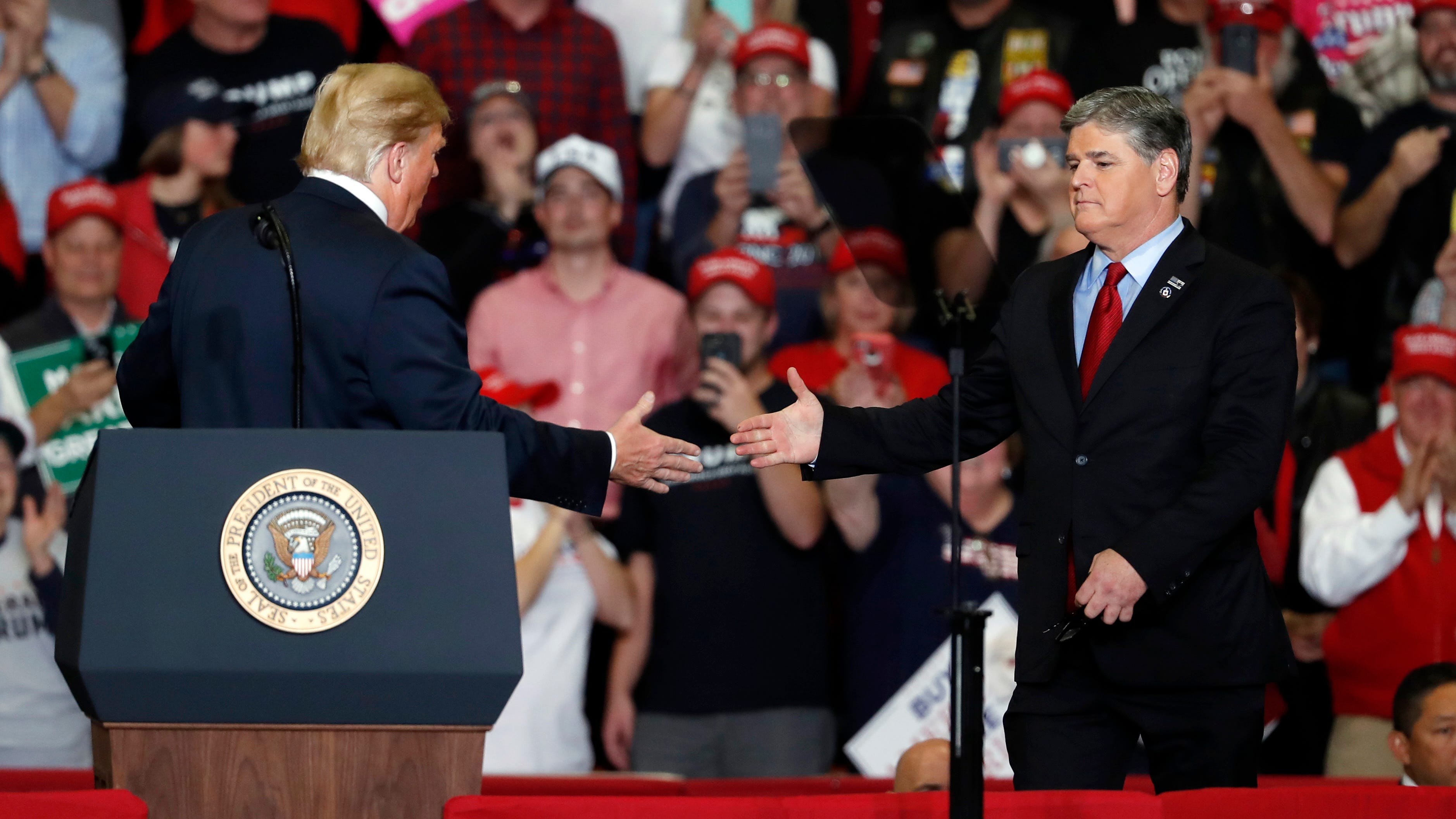 President Donald Trump shakes hands with Fox News Channel's Sean Hannity, right, during a campaign rally Monday, Nov. 5, 2018, in Cape Girardeau, Mo. (AP Photo/Jeff Roberson) ORG XMIT: MOJR128